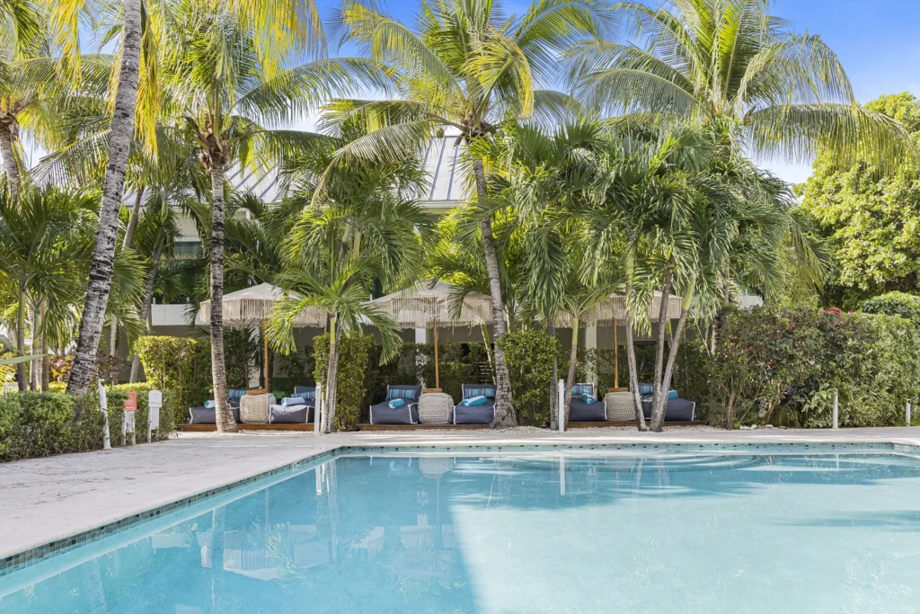 A pool bordered by palms and shaded loungers at The Oasis at Grace Bay.