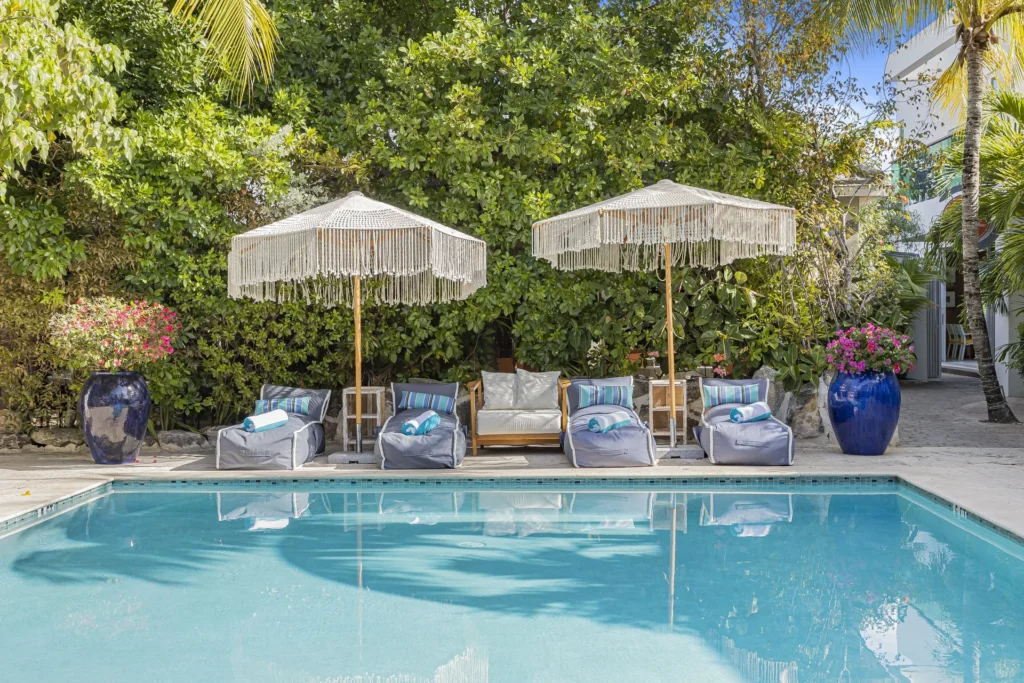 Swimming pool with loungers and fringed umbrellas at The Oasis at Grace Bay.